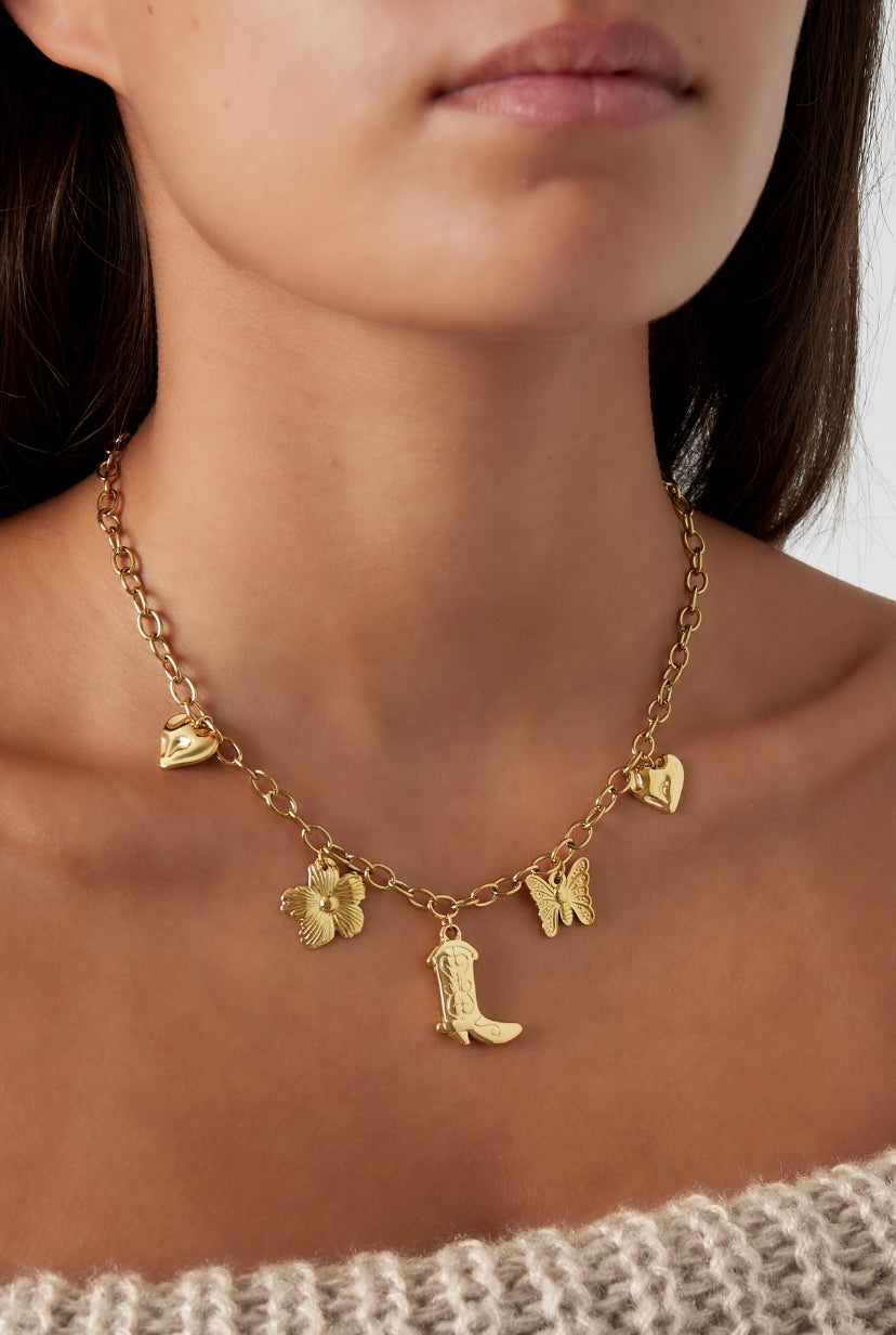 Bedelketting schakels verschillende bedels van cowboylaars, bloem, harten en vlinder goud op model