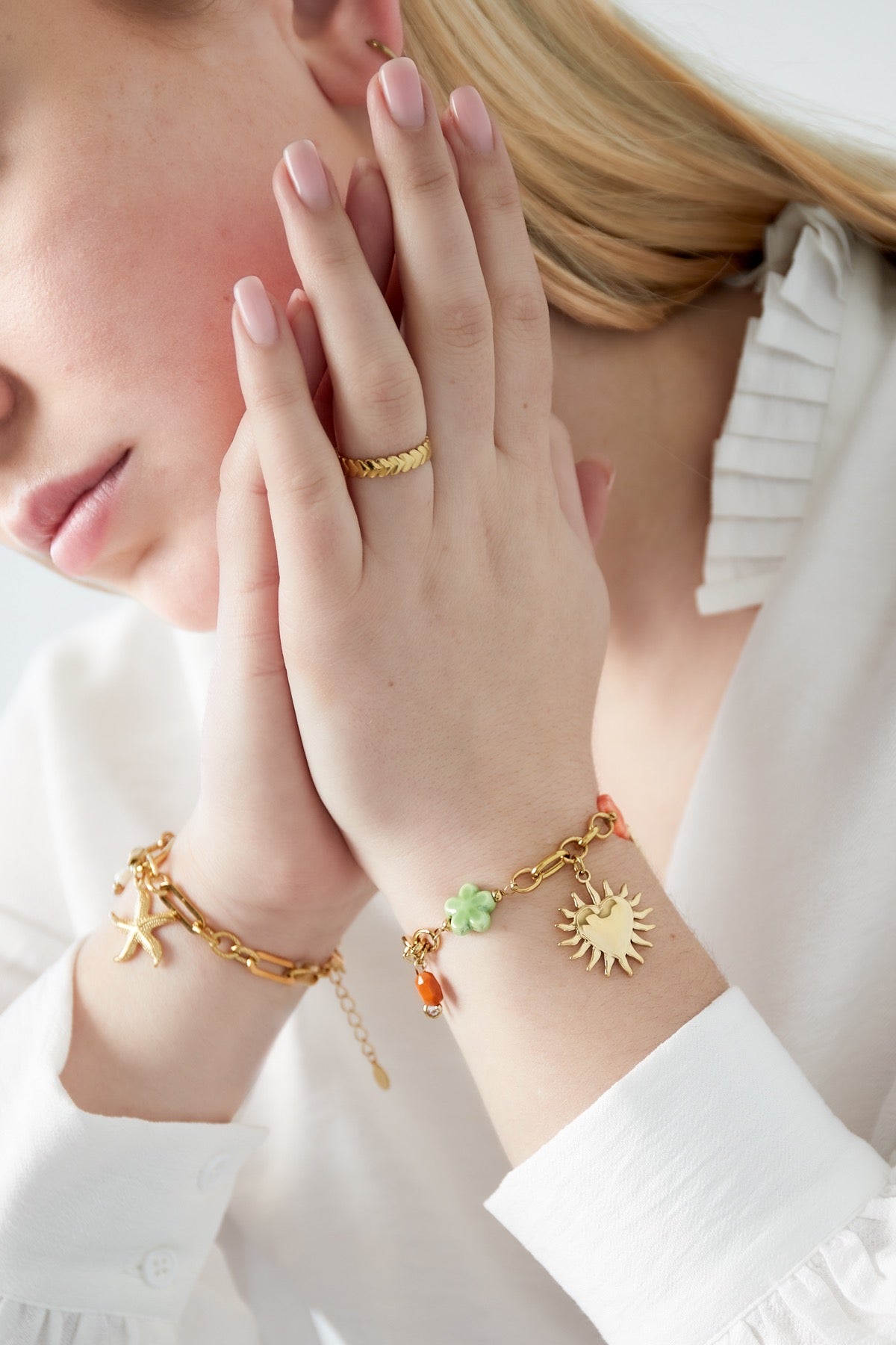 Schakelarmband met grove schakels en bedels van hartje, zon en bloem met kleurrijke details goud