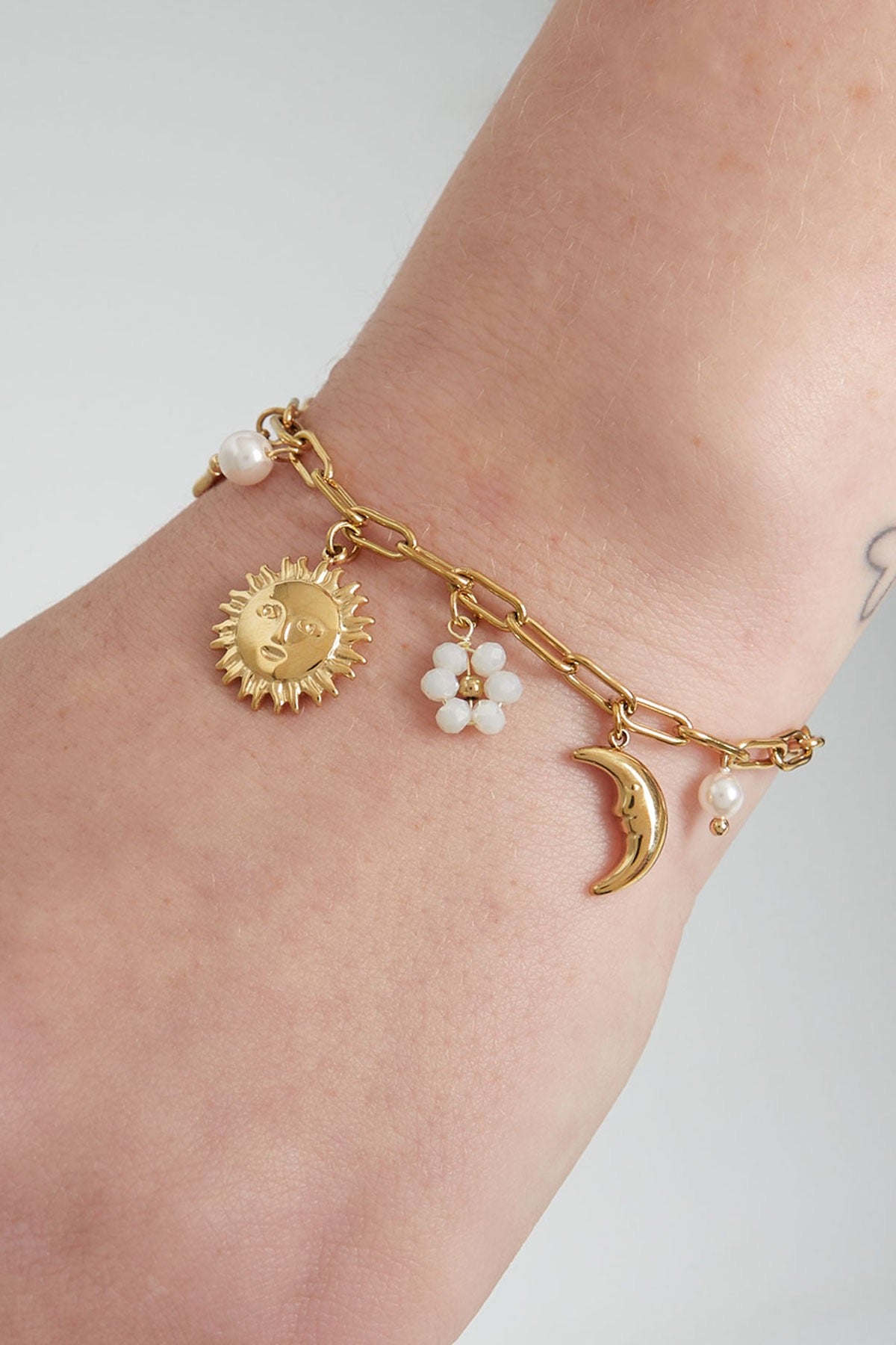 Schakelarmband met bedels van maan, bloem, parel en ster goud