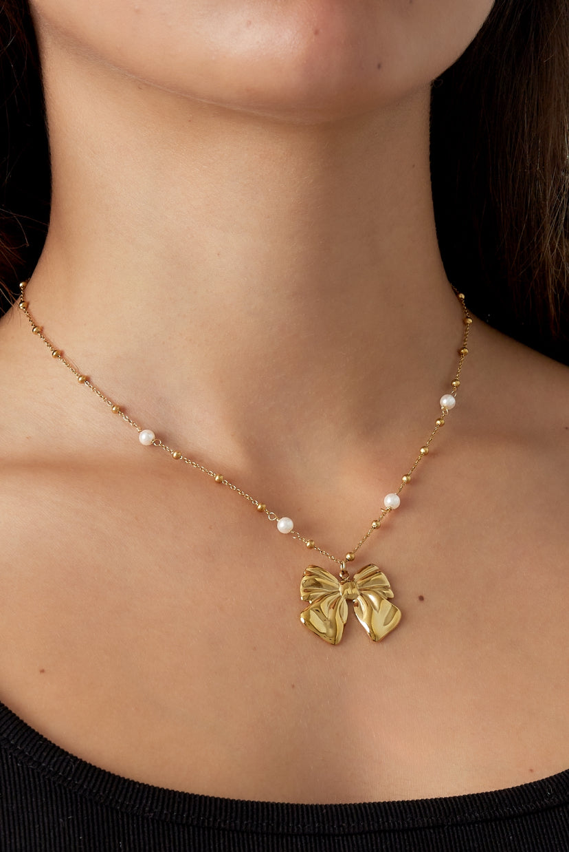 Subtiele ketting met hanger van strik in het goud op model