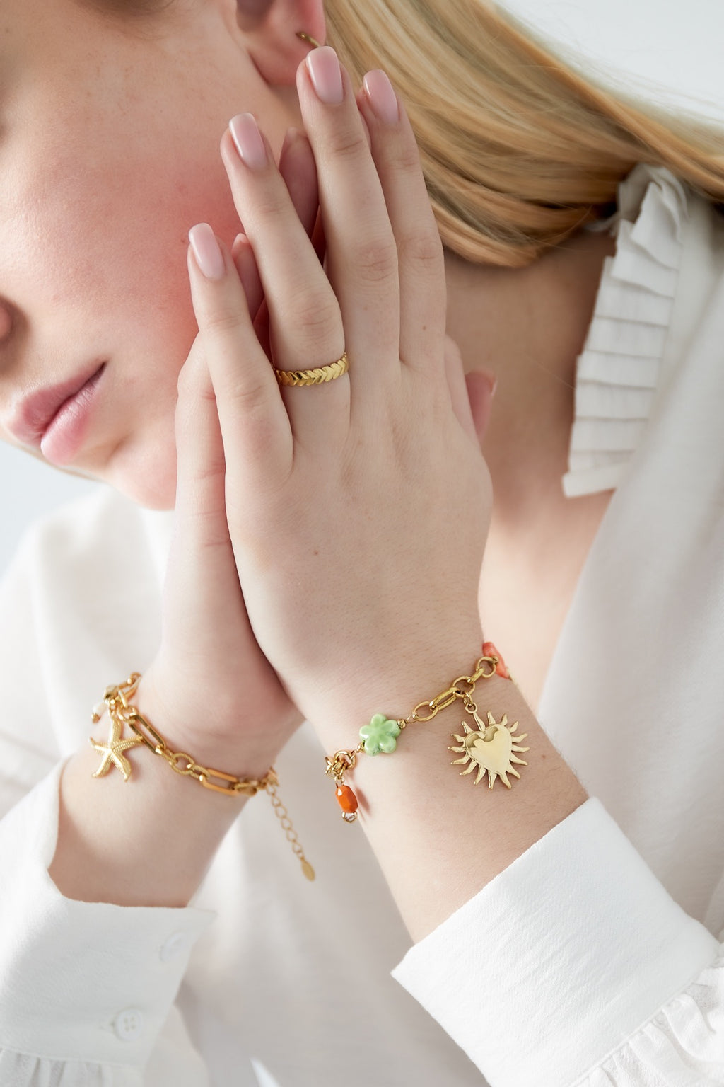 Schakelarmband met grove schakels en bedels van hartje, zon en bloem met kleurrijke details goud