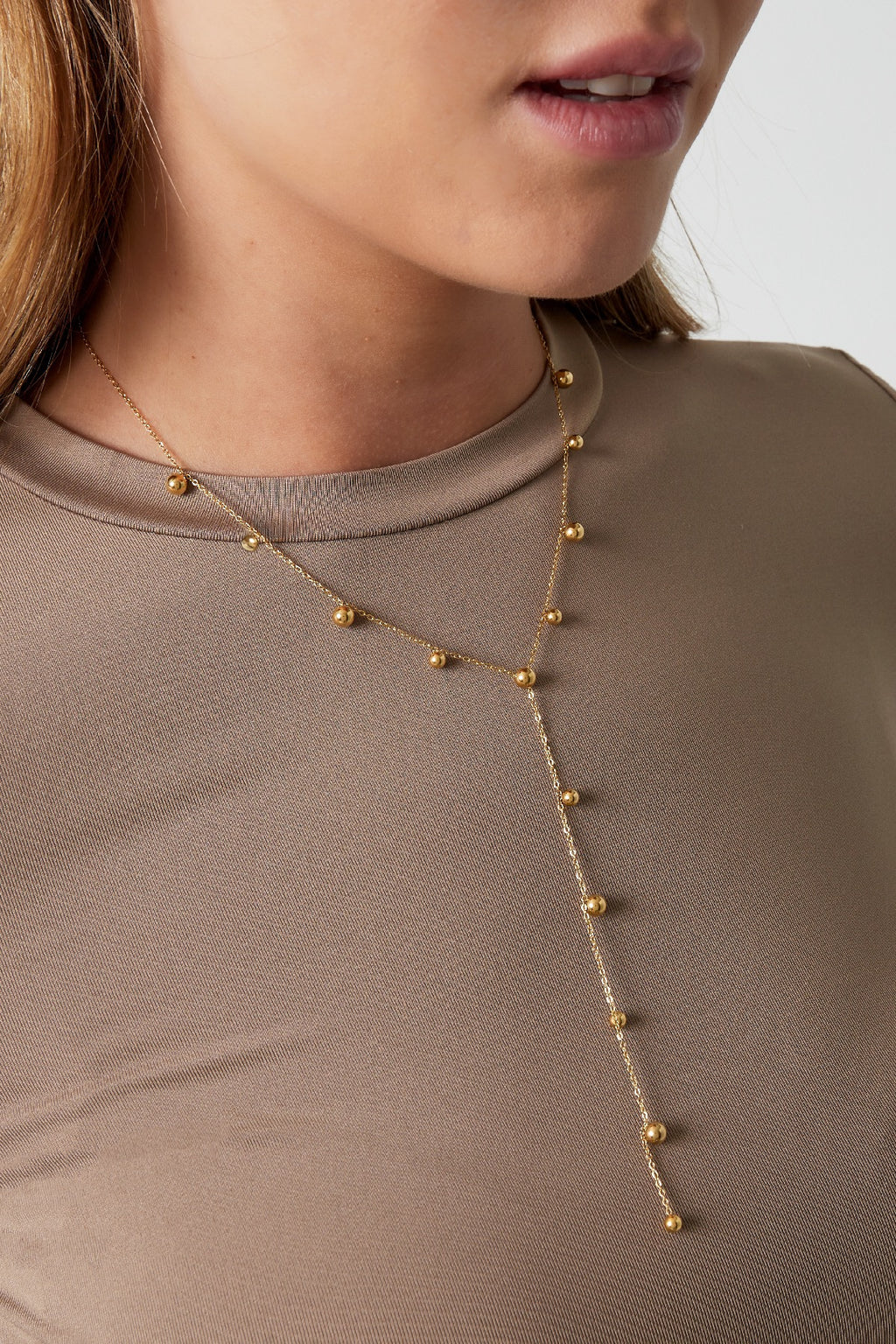 Lange ketting met bolletjes in het goud om hals