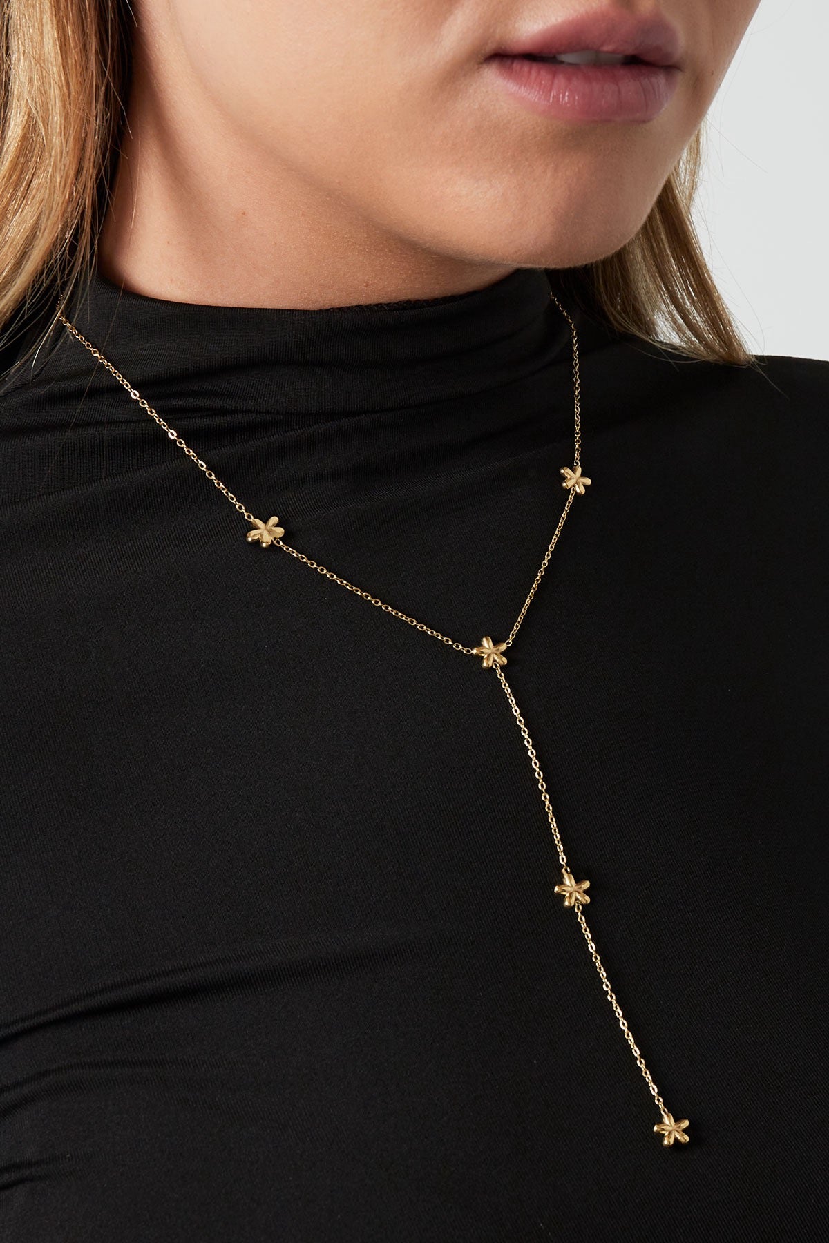 Lange minimalistische ketting met bloemen in het goud om hals van het model