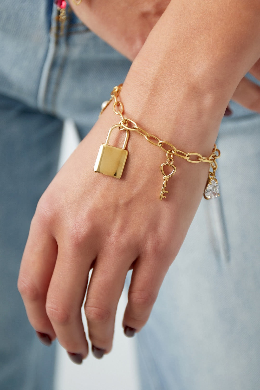 Schakelarmband met bedels in goud om pols