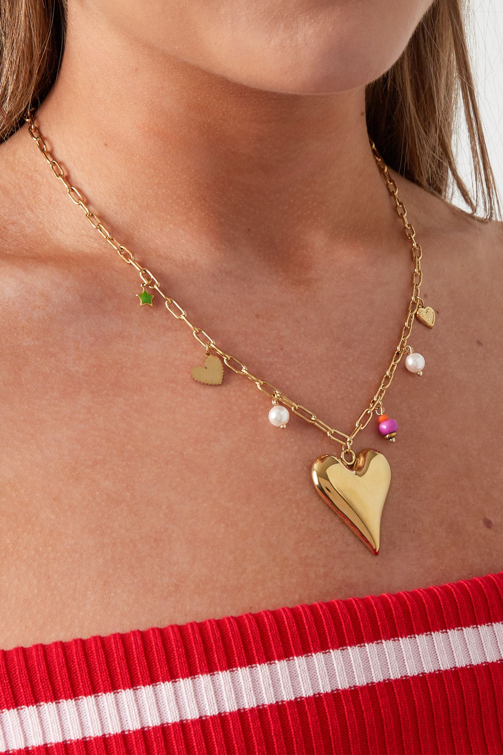 Bedelketting met hartjes bedels en parels in het goud om hals