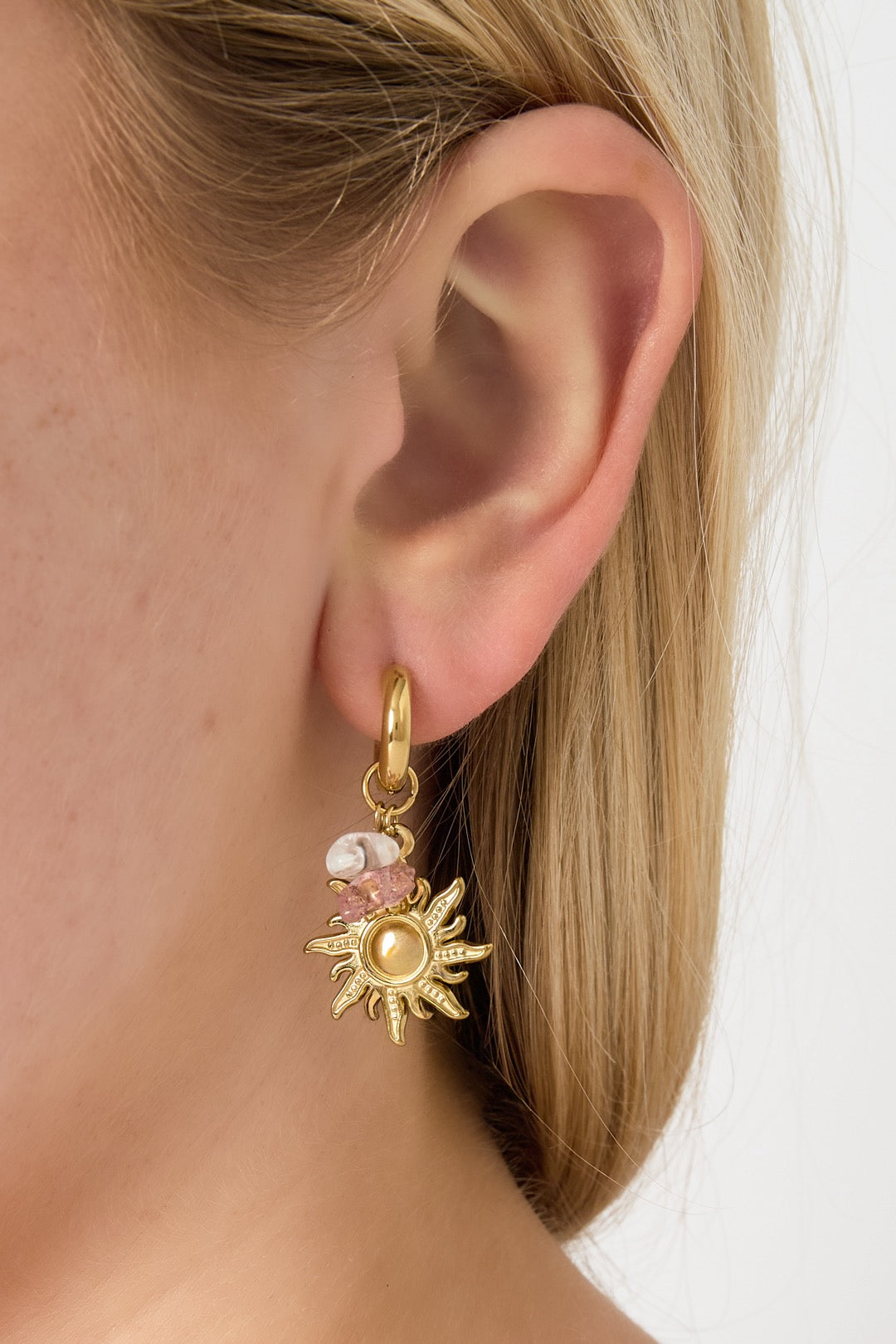 Oorbellen met zonnetjes en roze kralen goud in oor