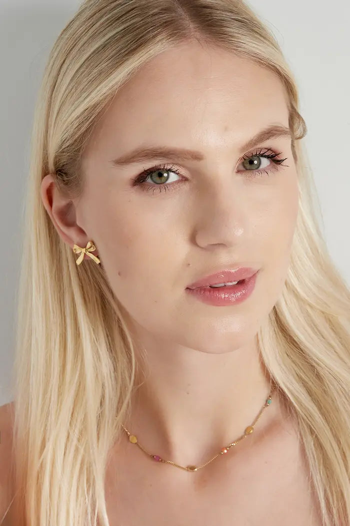 Oorbellen studs strikjes goudkleurig op model