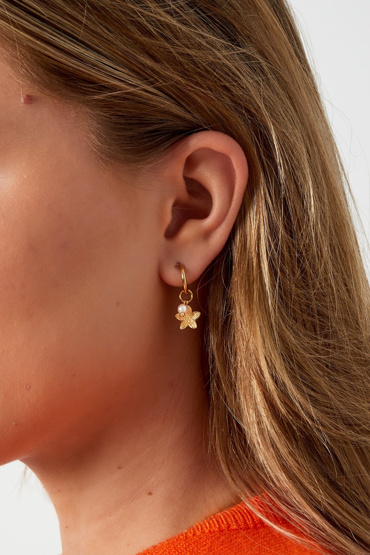 Oorbellen met bloem en parel hanger in het goud in oor