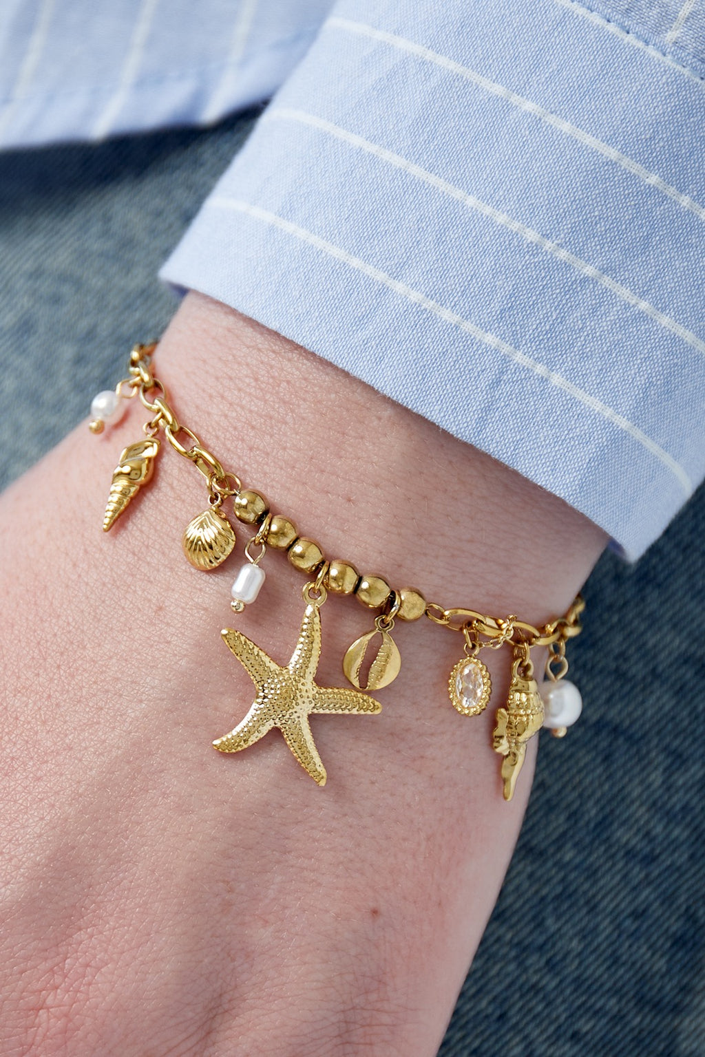 Bedelarmband met zomerse bedels van zeesterren en schelpen in het goud