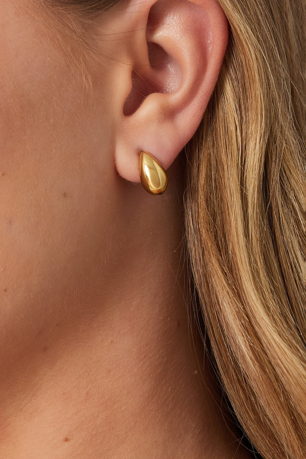 Kleine druppelvormige oorbellen in gouden kleur in oor