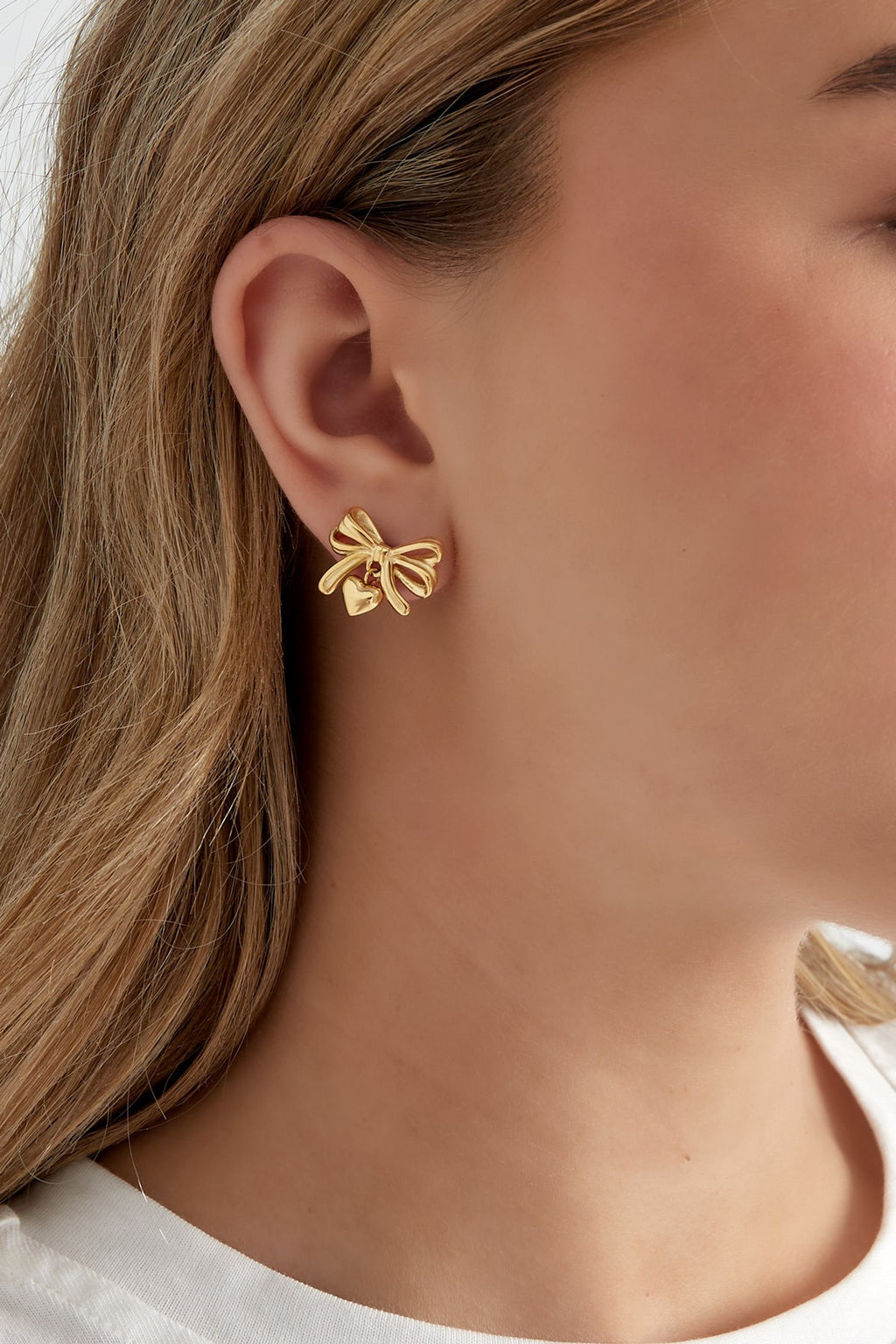 Trendy strikjes oorbellen met hartjes bedel in het goud